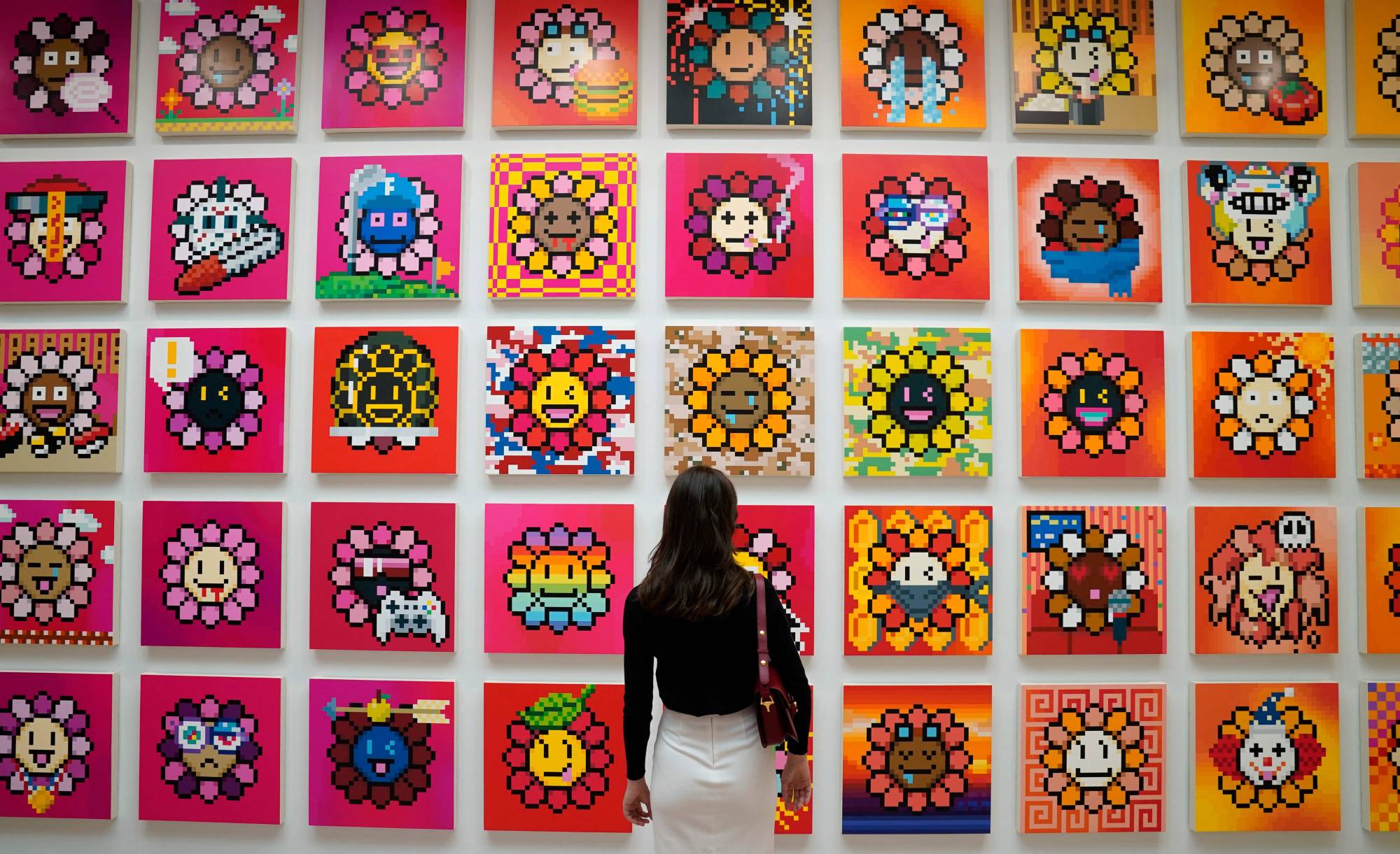 A person stands in front of artist Takashi Murakamis NFT project called Murakami Flowers during a press preview May 11, 2022 for An Arrow through History at Gagosians New York galleries. - This will be Murakami's first exhibition at Gagosian in New York since 2014 and represents his return to 980 Madison Avenue, where he had his inaugural exhibition with the gallery in 2007. (Photo by TIMOTHY A. CLARY / AFP) / RESTRICTED TO EDITORIAL USE - MANDATORY MENTION OF THE ARTIST UPON PUBLICATION - TO ILLUSTRATE THE EVENT AS SPECIFIED IN THE CAPTION